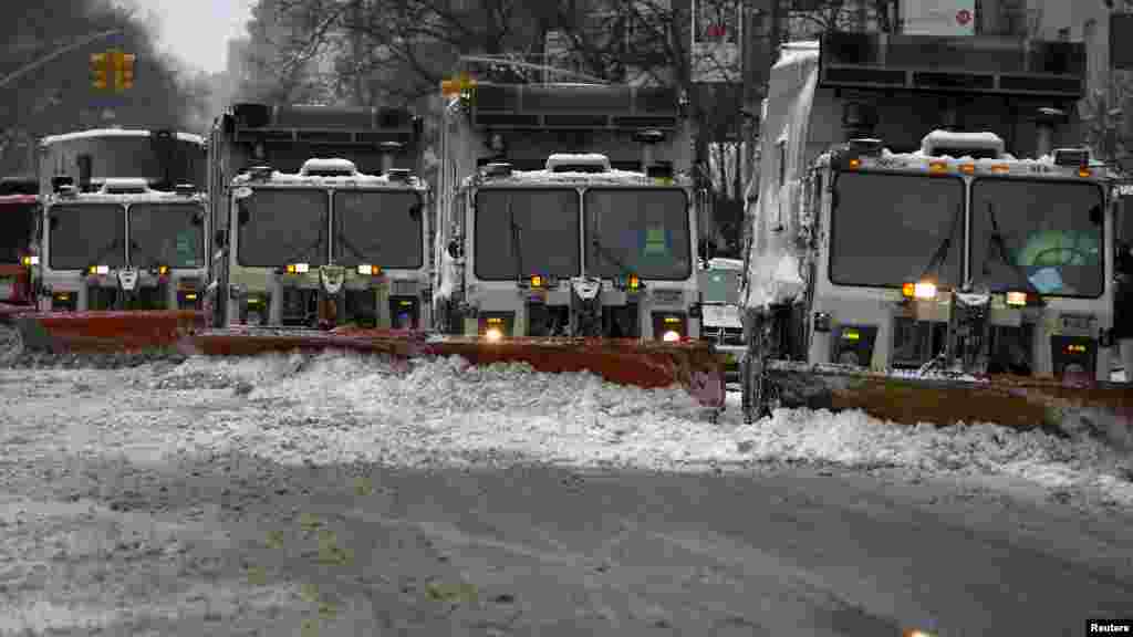 A line of snow plows make their way down 5th Avenue during what would normally be a busy rush hour morning following Winter Storm Juno in the Manhattan borough of New York, Jan. 27, 2015.