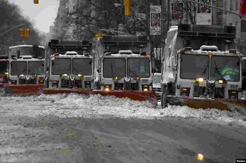 A line of snow plows make their way down 5th Avenue during what would normally be a busy rush hour morning following Winter Storm Juno in the Manhattan borough of New York, Jan. 27, 2015.