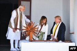 US President Donald Trump and First Lady Melania Trump listen to India's Prime Minister Narendra Modi (L) as they sit next to a charkha, or spinning wheel, during their visit at Gandhi Ashram in Ahmedabad on February 24, 2020.