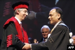 FILE - Partha Dasgupta (R), professor at Cambridge University in Britain, is awarded "Doctor Honoris Causa" by the university of Louvain-la-Neuve rector Bernard Coulie, Feb. 2, 2007.