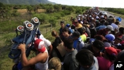 Un hombre levanta un carrito de bebé mientras cientos de migrantes intentan instalarse en la parte trasera de un camión, entre Niltepec y Juchitan, en el estado de Oaxaca, México, el 30 de octubre de 2018.