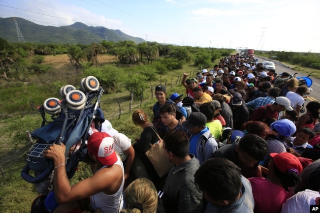 Un hombre levanta un carrito de bebé mientras cientos de migrantes intentan acomodarse en la parte trasera de un camión, entre Niltepec y Juchitan, en el estado de Oaxaca, México, el 30 de octubre de 2018.