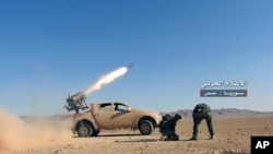 May 25, 2017 photo provided by the government-controlled Syrian Central Military Media, shows Syrian government troops firing multiple launcher rockets at insurgent group's position, in the Syrian province of Homs.
