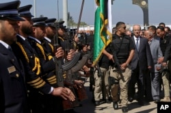 Palestinian Prime Minister Rami Hamdallah walks behind a bodyguard as he receives an honor guard on his arrival to the opening ceremony for a long-awaited sewage plant project east of Jebaliya, in the northern Gaza strip, March 13, 2018.