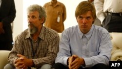Sergei Cherepanov, left, and Mikhail Antyufeev, two Russians kidnapped in Sudan's Darfur region in January 2015, wait at the airport in the Sudanese capital, Khartoum, after they were freed by their captors, June 6, 2015.