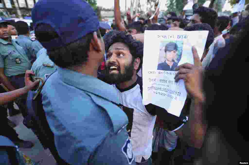 A relative argues with a member of the police as he shows a picture of a garment worker, who has been missing, during a protest demanding capital punishment for those responsible for the collapse of the Rana Plaza building in Savar, outside Dhaka, April 29, 2013.