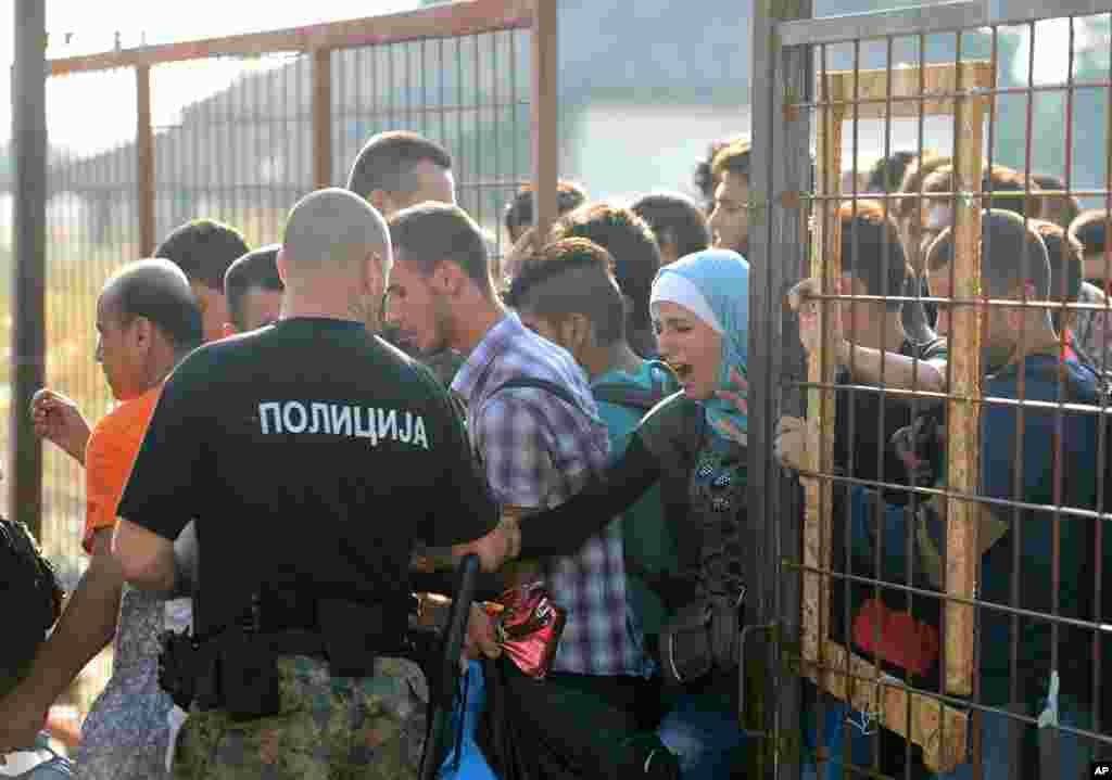 A Macedonian border policeman opens a gate for migrants to reach the southern Macedonian town of Gevgelija. Hundred of thousands migrants and refugees trying to reach the heart of Europe via Turkey, Greece, the Balkans and Hungary have faced dangers, difficulties and delays on every link of the journey.