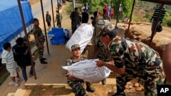 Nepalese soldiers load U.S. AID relief sacks at a staging area near Saturday's massive earthquake's epicenter in the town of Gorkha, Nepal, April 28, 2015.