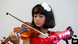 Isabella Nicola Cabrera, 10, plays her violin with her new prosthetic at the engineering department of George Mason University in Fairfax, Virginia, April 20, 2017. (AP Photo/Steve Helber)
