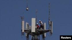 Workers install 5G telecommunications equipment on a T-Mobile US Inc tower in Seabrook, Texas.