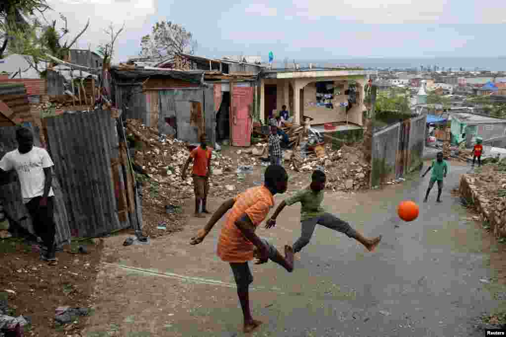 Warga bermain sepakbola di lokasi perumahan yang rusak akibat badai Matthew di kota Jeremie, Haiti.