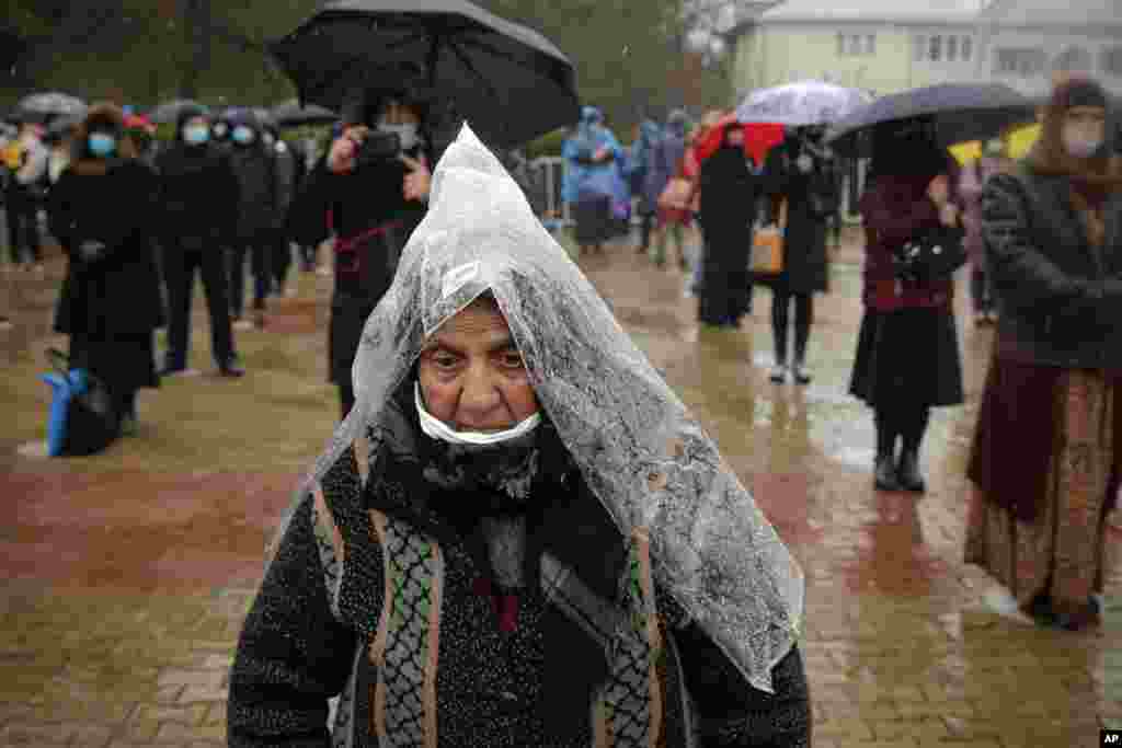 A woman using a plastic sheet as rain protection attends a religious service celebrating St. Andrew in the village of Ion Corvin, eastern Romania.&nbsp;Braving wintry weather and the new coronavirus fears, several hundred Orthodox Christian believers gathered outside a cave where St. Andrew is said to have lived and preached in the 1st century.&nbsp;