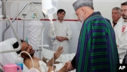 Afghan President Hamid Karzai talks with a victim wounded in a recent suicide bomb attack during an Ashura mourning procession, Kabul, Afghanistan, December 7, 2011.