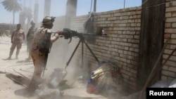 A member of the Iraqi security forces opens fire during clashes with fighters from Sunni militant group Islamic State of Iraq and the Levant (ISIL) in Ibrahim bin Ali village, west of Baghdad, June 24, 2014. Iraqi army soldiers clashed with militants from