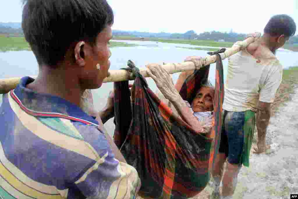 Rohingya refugees carry an old woman from Rakhine state in Myanmar near Teknaf in Bangladesh.