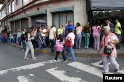 FILE - People wait in a line to buy staple goods outside a supermarket in Caracas, Venezuela, Oct. 20, 2015.