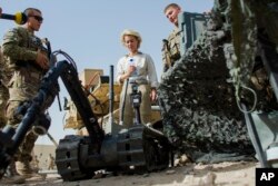 FILE - A U.S. soldier talks about the radio-controlled bomb disposal robot to visiting dignitaries during a demonstration of ground equipment at Camp Marmal outside Mazar-i-Sharif, Afghanistan, July 23, 2014.