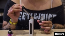 A woman adds flavor to a vaporizer while waiting for customers at the e-cigarette shop Henley Vaporium in New York, June 23, 2015. REUTERS/Lucas Jackson