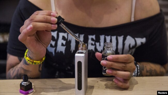 A woman adds flavor to a vaporizer while waiting for customers at the e-cigarette shop Henley Vaporium in New York, June 23, 2015. REUTERS/Lucas Jackson