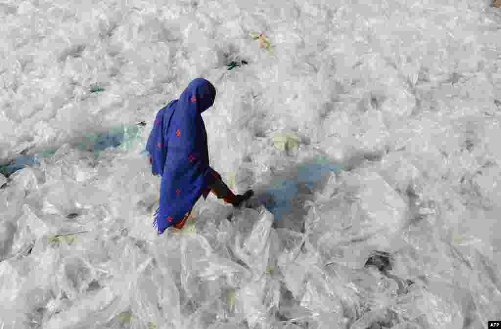 A Pakistan woman steps on recyclable plastic bags drying in the sun in Lahore, January 22, 2013.