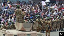Army soldiers stand on top of armored vehicles as they block anti-government protesters at a barricade during a demonstration demanding the ouster of Yemen's President Ali Abdullah Saleh in the southern city of Taiz, April 11, 2011