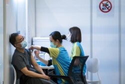 Seorang pria menerima suntikan vaksin COVID-19 buatan perusahaan farmasi China, Sinovac, di sebuah pusat vaksinasi di Hong Kong, 23 Februari 2021. (Foto: Paul Yeung/AFP)