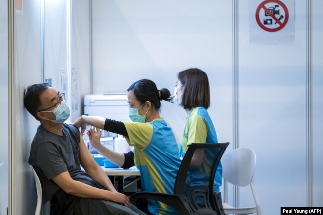 Seorang pria menerima suntikan vaksin COVID-19 buatan perusahaan farmasi China, Sinovac, di sebuah pusat vaksinasi di Hong Kong, 23 Februari 2021. (Foto: Paul Yeung/AFP)