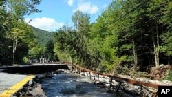 Floodwaters caused by Tropical Storm Irene rush along Route 73 in St. Huberts, New York tearing up the road as they flow, August 29, 2011