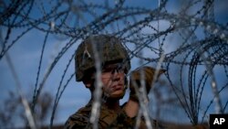 A soldier agent sets up barbed wire at the San Ysidro port of entry, at the U.S.-Mexico border, seen from Tijuana, Mexico, Nov. 22, 2018.