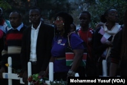 Mourners, some wearing national colors, carry white crosses — 148 of them, symbolizing those killed in the Garissa University College attack last week in Kenya.