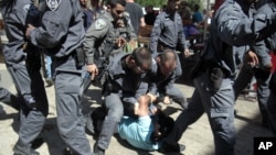 Israeli police officers detain a Palestinian man as Israeli youths enter Jerusalem's Old City through Damascus Gate during a march celebrating Jerusalem Day, Sunday, May 17, 2015.