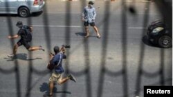 ရဲတွေလိုက်လံဖမ်းဆီးမှုကြောင့် မြန်မာသတင်းထောက်နဲ့ ဆန္ဒပြသူတချို့ ထွက်ပြေးနေတဲ့မြင်ကွင်း ( ပုံဟောင်း - February 27, 2021. REUTERS/Stringer )