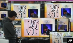 FILE - South Korean professional Go player Lee Sedol is seen on the TV screens in a matchup with Google's artificial intelligence program, AlphaGo, at the Yongsan Electronic store in Seoul, South Korea, March 9, 2016.