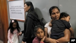 FILE - Asylum seekers Nadeeka Dilrukshi Nonis, right, with her son Dinath and daughter Sethmundi Kellapatha and Vanessa Mae Rodel with her daughter Keana wait at the office of Torture Claims Appeal Board in Hong Kong Monday, July 17, 2017.