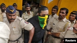 An accused man (face covered), surrounded by Indian policemen, is taken to a court in Mumbai, India, Sept. 11, 2015. 