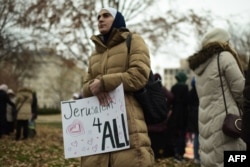 FILE - A woman carries a poster reading "Jerusalem for All" as Muslim worshippers gathered in front of the White House for Friday prayers in Washington to protest President Donald Trump's declaration of Jerusalem as Israel's capital, Dec. 8, 2017.