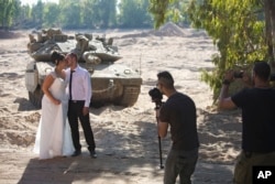Noga and Moshiko Siho pose for wedding photos in an Israeli army staging area on the border near Kibbutz Yad Mordechai, Aug. 27, 2014.