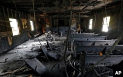 Burned pews, destroyed musical instruments, Bibles and hymnals are part of the debris inside the fire damaged Hopewell M.B. Baptist Church in Greenville, Mississippi, Nov. 2, 2016. A Mississippi mayor is calling it a hate crime as arson investigators collect evidence at a black church that was heavily damaged by fire and tagged with "Vote Trump" in silver spray paint.