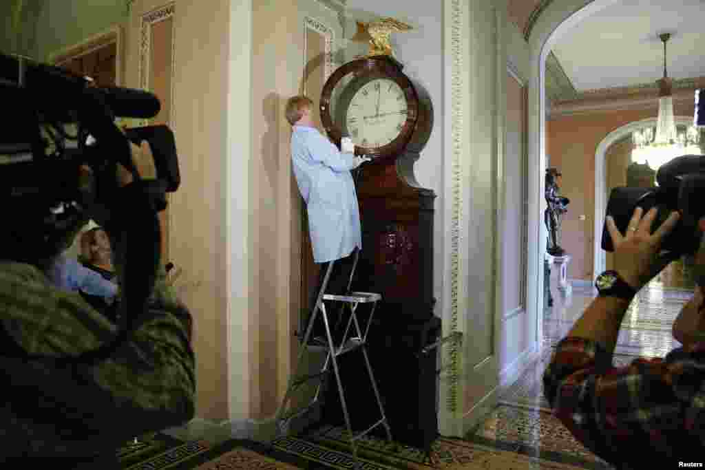 Richard Doerner, a museum specialist for the U.S. Senate, restarts the historic Ohio Clock outside the Senate floor at the U.S. Capitol in Washington, D.C. The clock had stopped during the sixteen-day government shutdown, when the staff members who wind it were furloughed as non-essential staff.