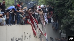 Des manifestants escaladant le mur de l'ambassade américaine au Caire