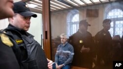 Founder of the Baring Vostok investment fund Michael Calvey (C) sits behind a cage glass window as he waits for the session in a court room in Moscow, Russia, Feb. 16, 2019.