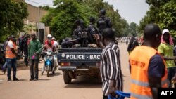 FILE - Police officers drive by during a march called by the opposition to protest the worsening security situation, in Ouagadougou, on July 3, 2021. 