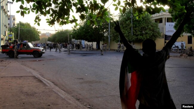 A Sudanese protester chants slogans as security forces prepare to disperse them along a street during demonstrations in central Khartoum, Sudan, May 15, 2019.