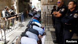 Palestinian men pray as Israeli forces secure the compound known to Muslims as Noble Sanctuary and to Jews as Temple Mount, in Jerusalem's Old City July 26, 2017.