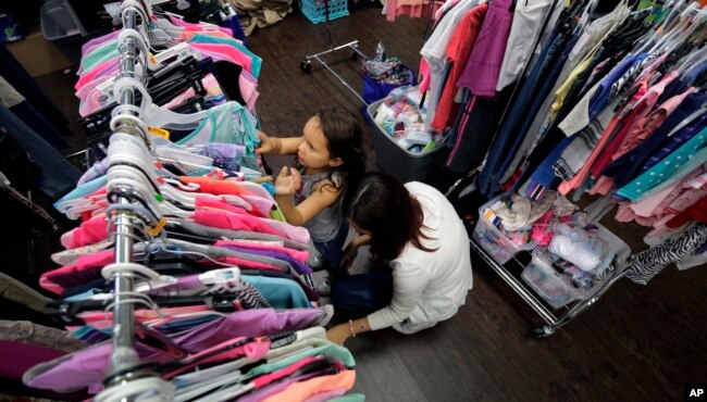 Immigrants seeking asylum, Natalia Oliveira da Silva and her daughter, Sara, 5, look through donated clothing at a Catholic Charities facility, July 23, 2018, in San Antonio, Texas.