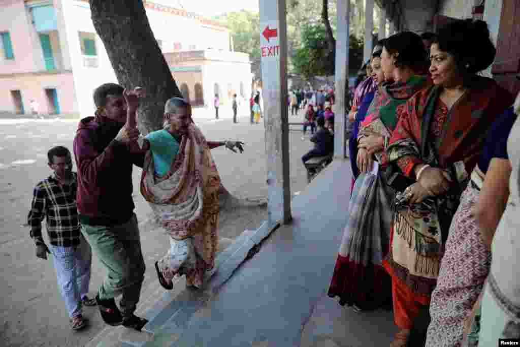 ایک شخص بوڑھی عورت کو پولنگ اسٹیشن ووٹ ڈالنے کے لیے لا رہا ہے۔