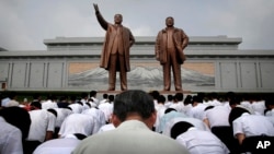 North Koreans bow in front of bronze statues of the late leaders Kim Il Sung, left, and Kim Jong Il at Munsu Hill in Pyongyang, North Korea, July 27, 2015. These two bronze statues were created by artists from Mansudae Art Studio.