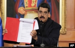 Venezuela's President Nicolas Maduro holds a document as he speaks during a ceremony at Miraflores Palace in Caracas, May 1, 2017.