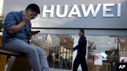 一名男子在北京一家华为商店外同时使用两只手机。（2019年5月20日）
