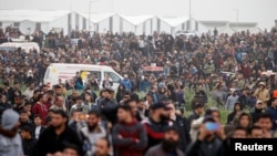 Palestinians are seen gathered during a protest marking Land Day and the first anniversary of a surge of border protests, at the Israel-Gaza border fence east of Gaza City, March 30, 2019. 